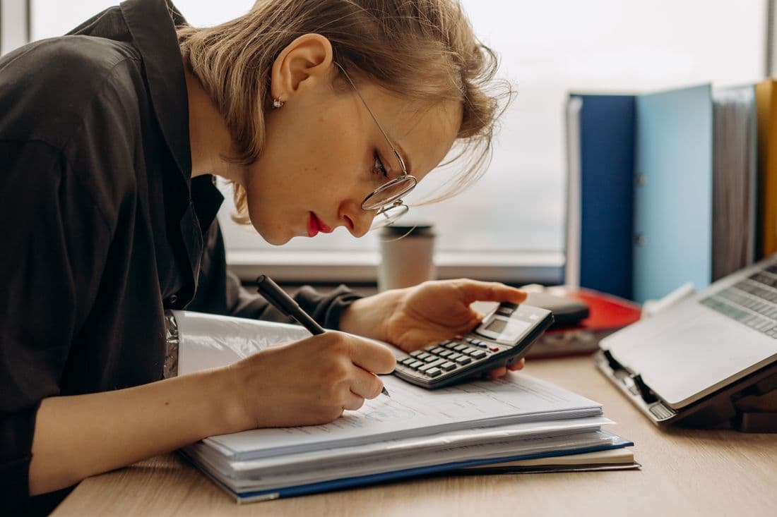 A bookkeeper posting entries with a calculator and documents