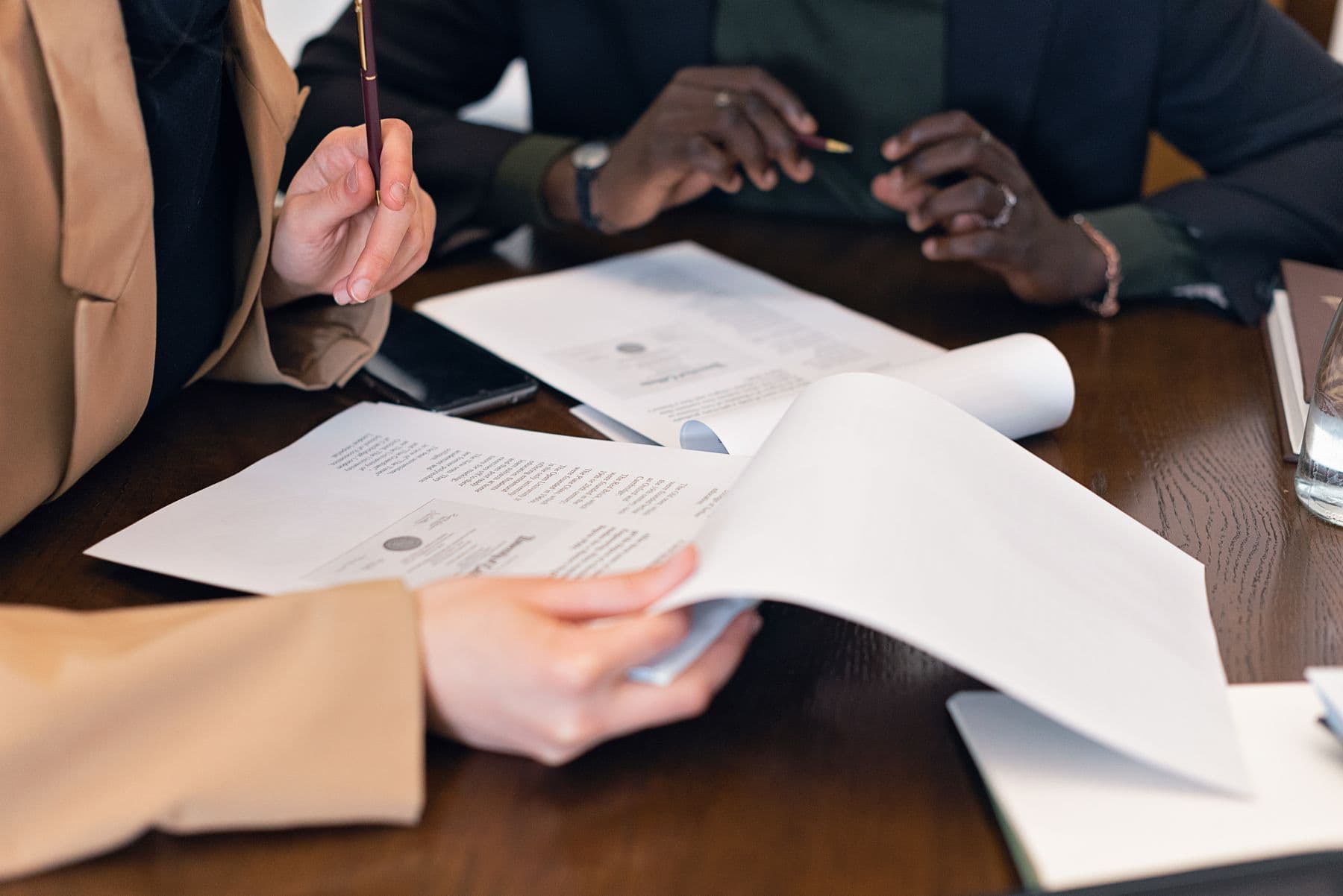 Two advisors reviewing a client's paperwork across a boardroom table