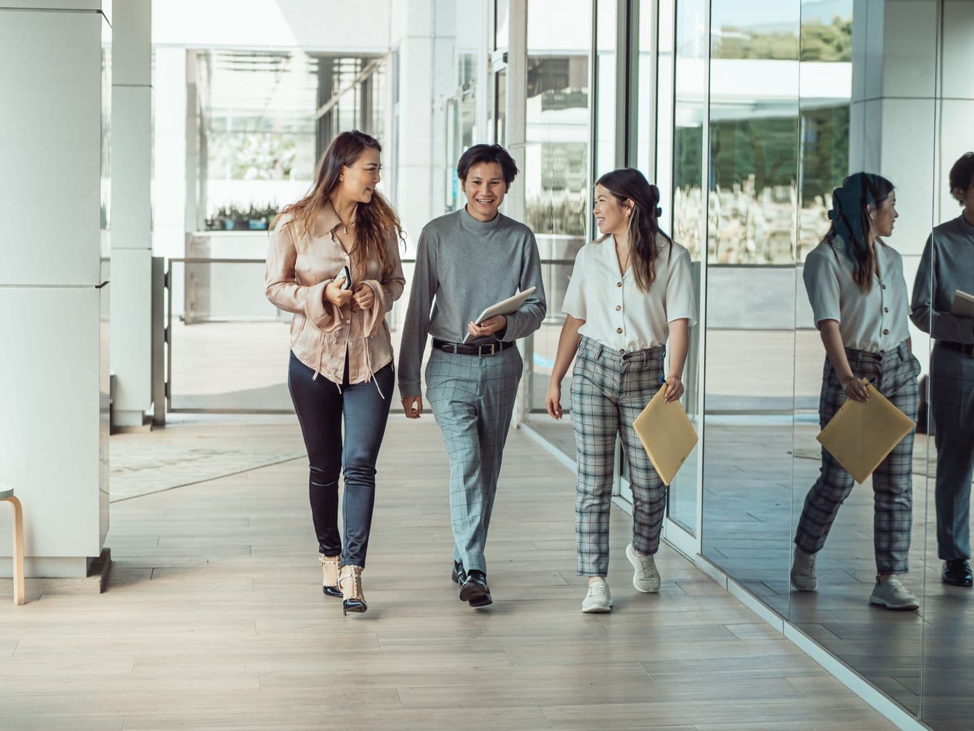 Three colleagues walking and talking through a modern office lobby