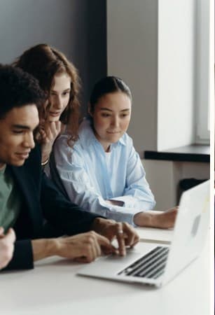 Three advisors working through a client's numbers at a laptop