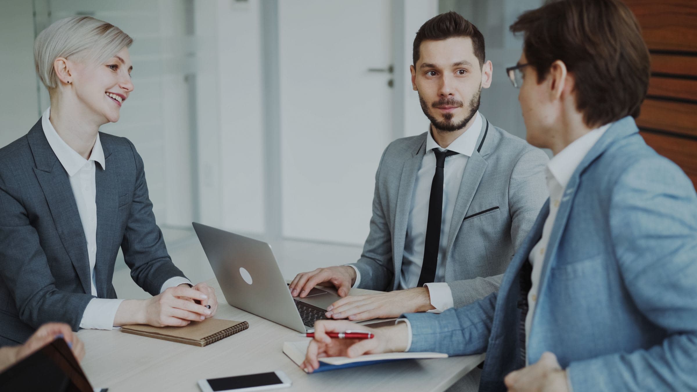 Three advisors talking a client through their options around a meeting table