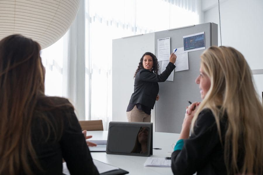 A consultant explaining a structure at a whiteboard to two colleagues