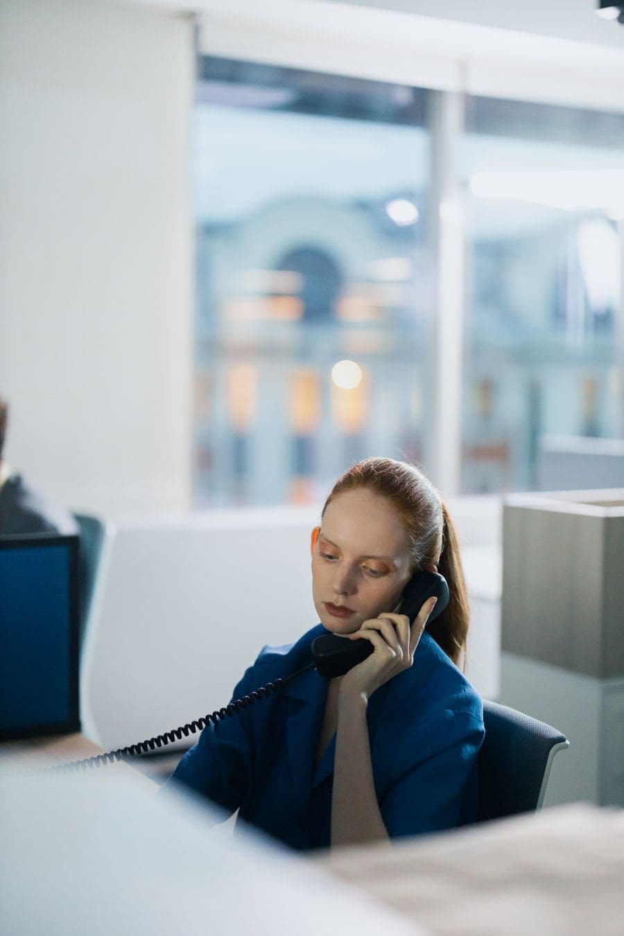 A professional taking a call at her desk in an open-plan office