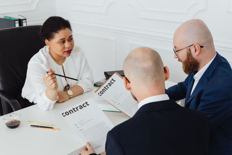 Three people reviewing a contract across a meeting table