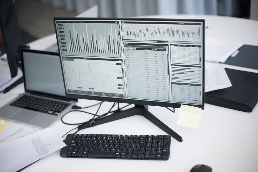 A workspace of monitors showing financial charts