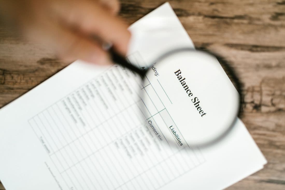 A balance sheet being read under a magnifying glass