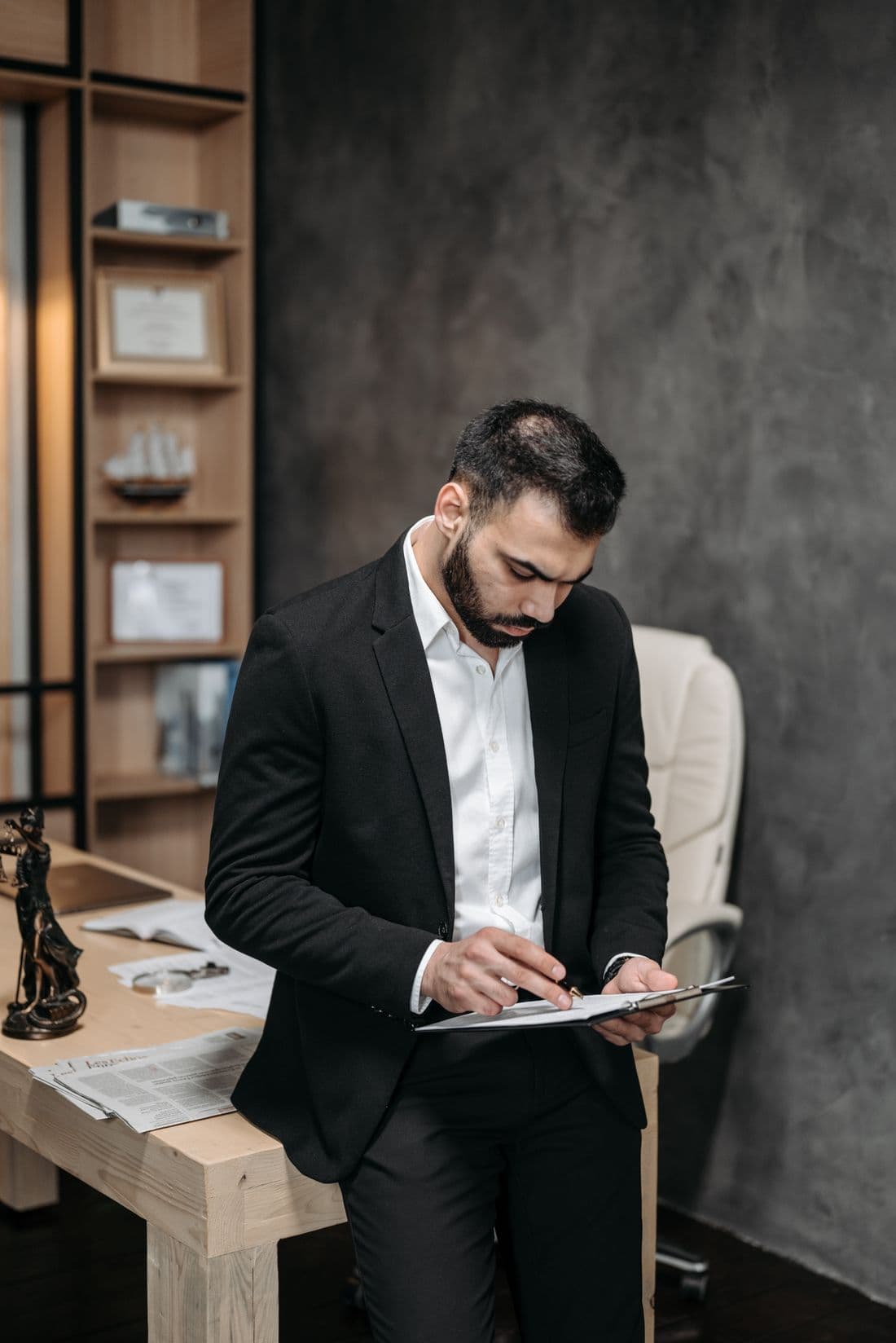 A professional checking paperwork against a register at a desk