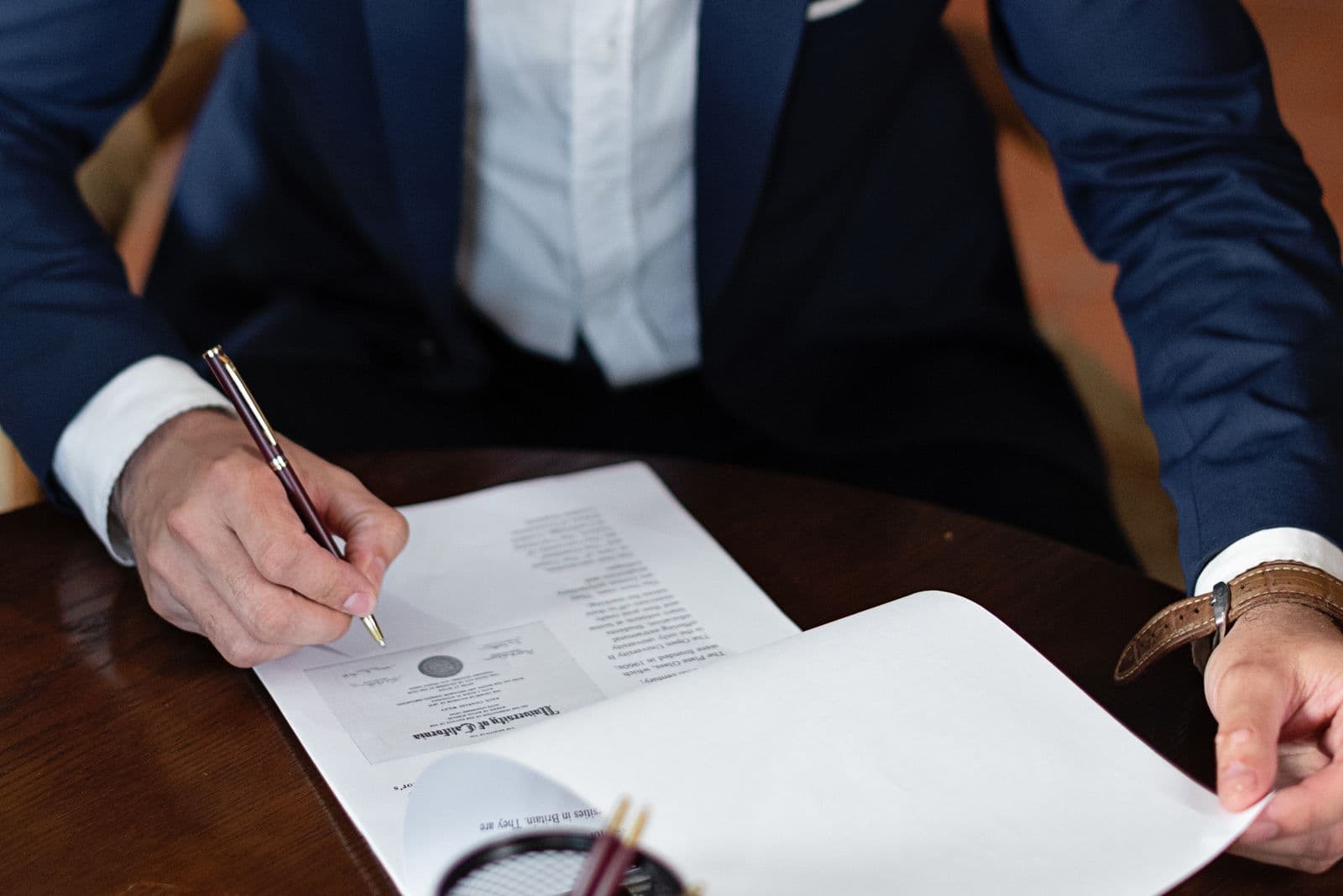 A corporate document with an official seal being signed at a desk