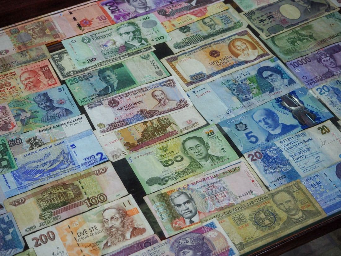 Banknotes from many countries laid out in rows on a table